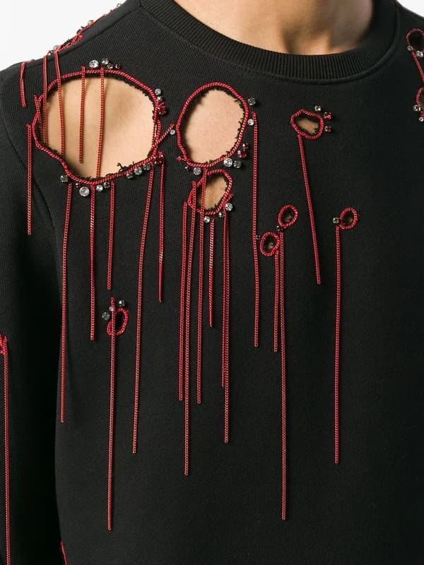 A black jumper with cut-outs edged in red beading and hanging red cords