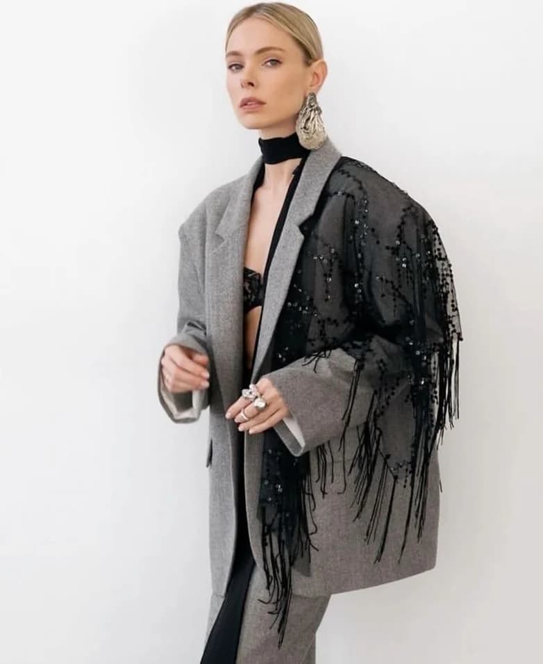 A grey wool coat with one side reworked in black sequins and fringe
